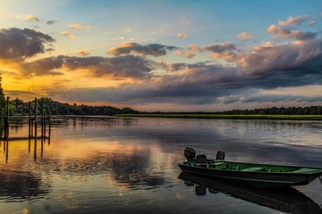 Idealized Artistic focus of a beautiful sunset over a river with a dock and lily pads in foreground with colorful cloudscape