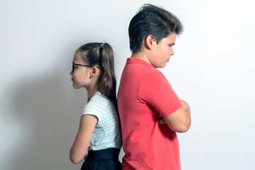 The boy resents the little girl. Children stand with their backs to each other. Brother and sister disappointed