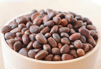 Inshell pine nuts in a wooden bowl closeup