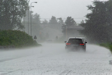 The strong storm with heavy rain on the road with poor visibility of cars. Concept of the danger of driving in bad weather