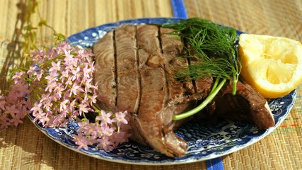 Close-up shot of delicious tuna fish grilled on barbecue grill, lying on the plate. 4K