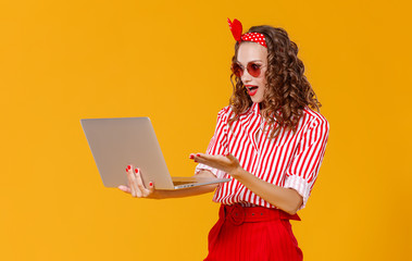 funny cheerful woman with laptop on yellow background.