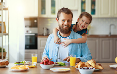 happy family father with child  feeds his   daughter in kitchen with Breakfast