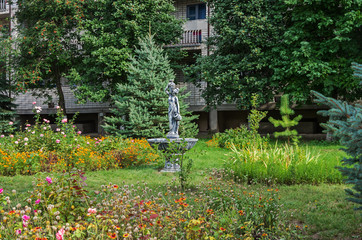 Fototapeta premium Flowerbed and sculpture in form of fountain