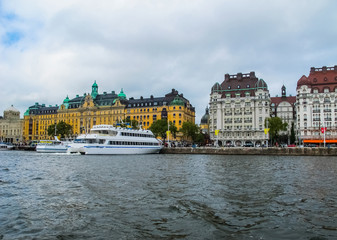 Naklejka premium Panoramic view from the tourist excursion boat to the pier with boats and the beautiful buildings of Stromkayen in the center of Stockholm Sweden