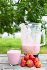 A glass of fresh cold smoothie with berries and cherrys on a wooden table, summer set, outdoor greed blured background,boke.