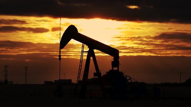 Pump jack. Oil well. Crude oil economy. Oil well, close up. Silhouette of an oil pump jack on rig as the sun sets in the background. 