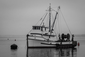 Black and white image of an old fishing boat moored in the Monterey Harbor and Marina along the Monterey Bay of central California.