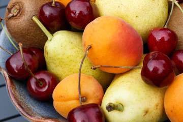 Naklejka na ściany i meble Pears, apricots, kiwi and cherries in a bowl during summer