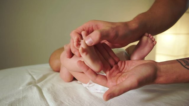 careful masseur hands massages small baby foot slow