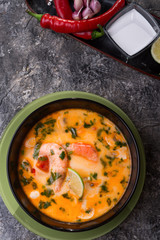 famous delicious Thai Tom yum spicy soup with shrimps and coconut milk on black table. close up. flat lay