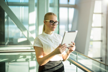 Woman in glasses proud economist online payment via touch pad while standing inside enterprise....