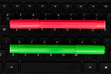 Pink pen and green marker on keyboard