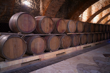 Vintage wine brown barrels with expensive tasty red wine. An old wine cellar in the center of...
