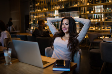 Happy smiling business woman having online video conference via laptop computer while relaxing in restaurant 