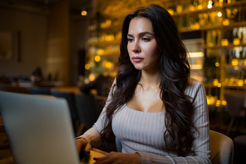 Serious successful business woman having online training course via laptop computer while sitting in restaurant during work break 