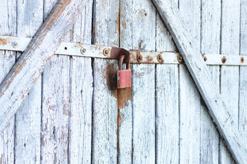 Old gray wooden plank gate with a padlock.