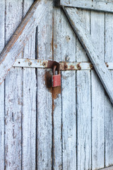 Old gray wooden plank gate with a padlock.