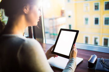 Female skilled publication specialist holding touch pad with empty mock up copy space screen background for promotional content while sitting at workplace in office. Blogger using digital tablet