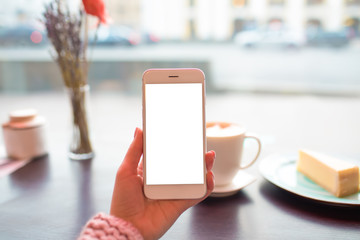 Closeup woman holding contemporary smartphone with empty mock up copy space screen background for promotional content while sitting in coffee shop during leisure in winter holidays. Online banking