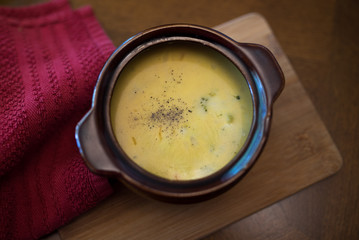 broccoli cheese soup served in a brown bowl 