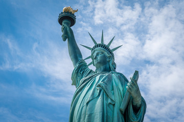 Shot of the Statue of Liberty in New York City, Usa. The shot is taken during a beautiful sunny day with a blue sky and white clouds in the background