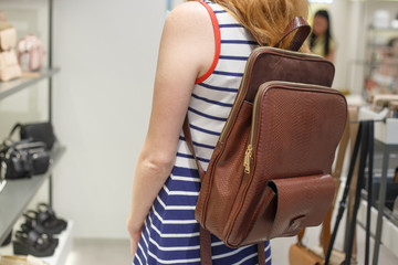 Woman choosing leather backpack at shop