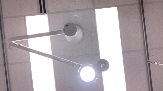 A patient's view of a doctor adjusting the ceiling operating room light.  	