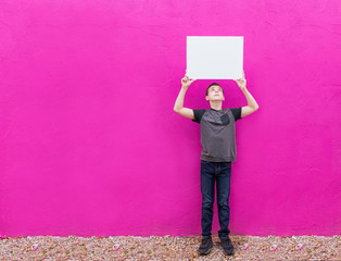 isolated cute boy holding blank white sign with space on colorful bright background