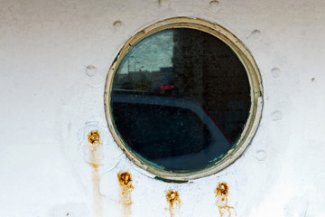 Vintage old porthole window with a reflection of the shore on the glass
