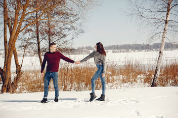 Fototapeta na wymiar Cute couple have fun. Boy and girl in a winter park. Man in a red sweater. Brunette in a gray sweater