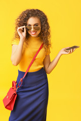 Stylish African-American with mobile phone on color background