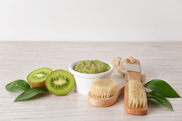 Scrub with kiwi and brushes on white wooden table