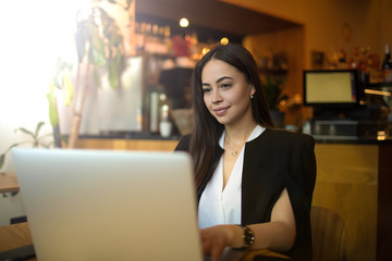 Gorgeous woman distance manager checking e-mail via laptop computer, sitting in restaurant during...