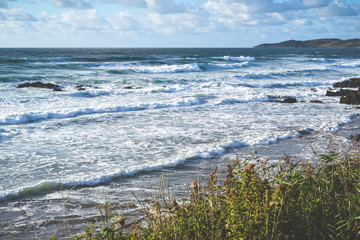 Waves breaking on the beach at high tide on the shore in North Devon UK