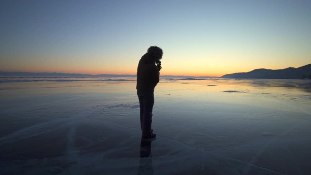 Full length of tourist photographing beautiful sunset at Lake Baikal against sky