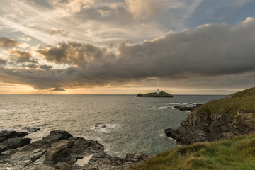 Godrevy Lighthouse at sunset with beautiful cloudy sky and warm glow, Cornwall, UK