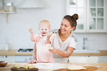 little girl and young woman play with flour on kitchen countertop, family scene, family fun