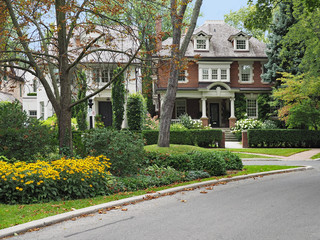 Tree-lined residential street with large brick detached houses