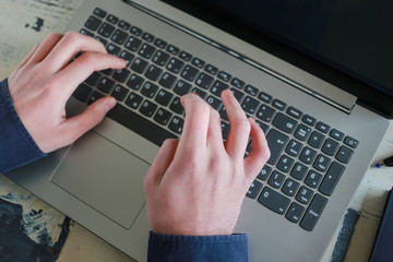 Young employee working on the laptop. Male hands typing on the keyboard