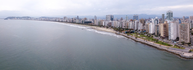 Beautiful aerial drone view of Santos city in Sao Paulo, Brazil. Panoramic Santos skyline with beach, sea, streets and buildings with mountains in the background in foggy day.