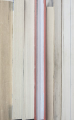 A vertical stack of books. An old pile of books completely fill the space, inside close up.