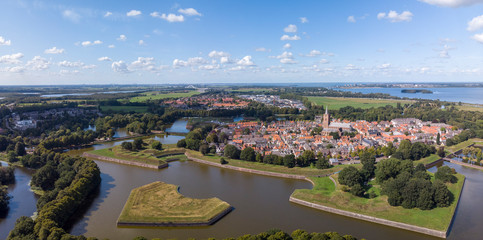 Aerial panoramic view on the fortification city Naarden Vesting with its defensive constructions surrounding the village against a blue sky with clouds