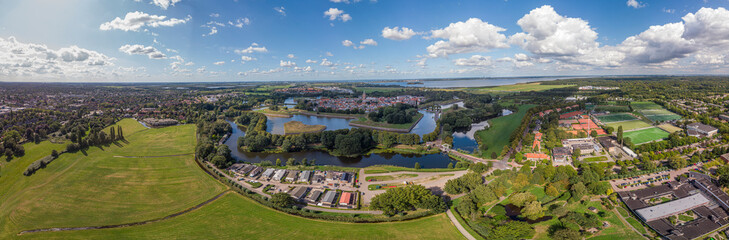 Aerial 360 panoramic view on the fortification city Naarden Vesting below a cloud with its defensive constructions surrounding the village against a blue sky with clouds passing