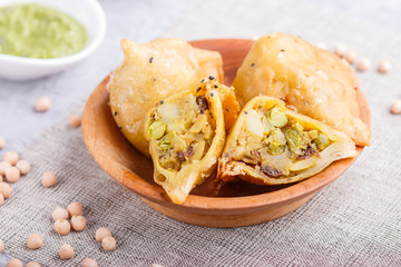 traditional indian food samosa in wooden  plate with mint chutney on a gray concrete background. side view.