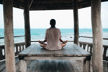 young woman meditating in a yoga pose at the beach