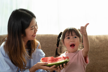 Happy Asian child enjoy eating a ripe juicy watermelon with her older sister