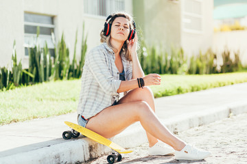 Portrait of beautiful woman with skateboard in the city.