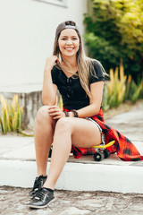 Portrait of smiling young female skateboarder with her skateboard outdoors