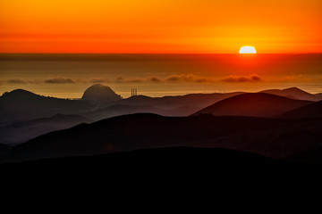 Setting Sun in Ocean, silhouetted hills